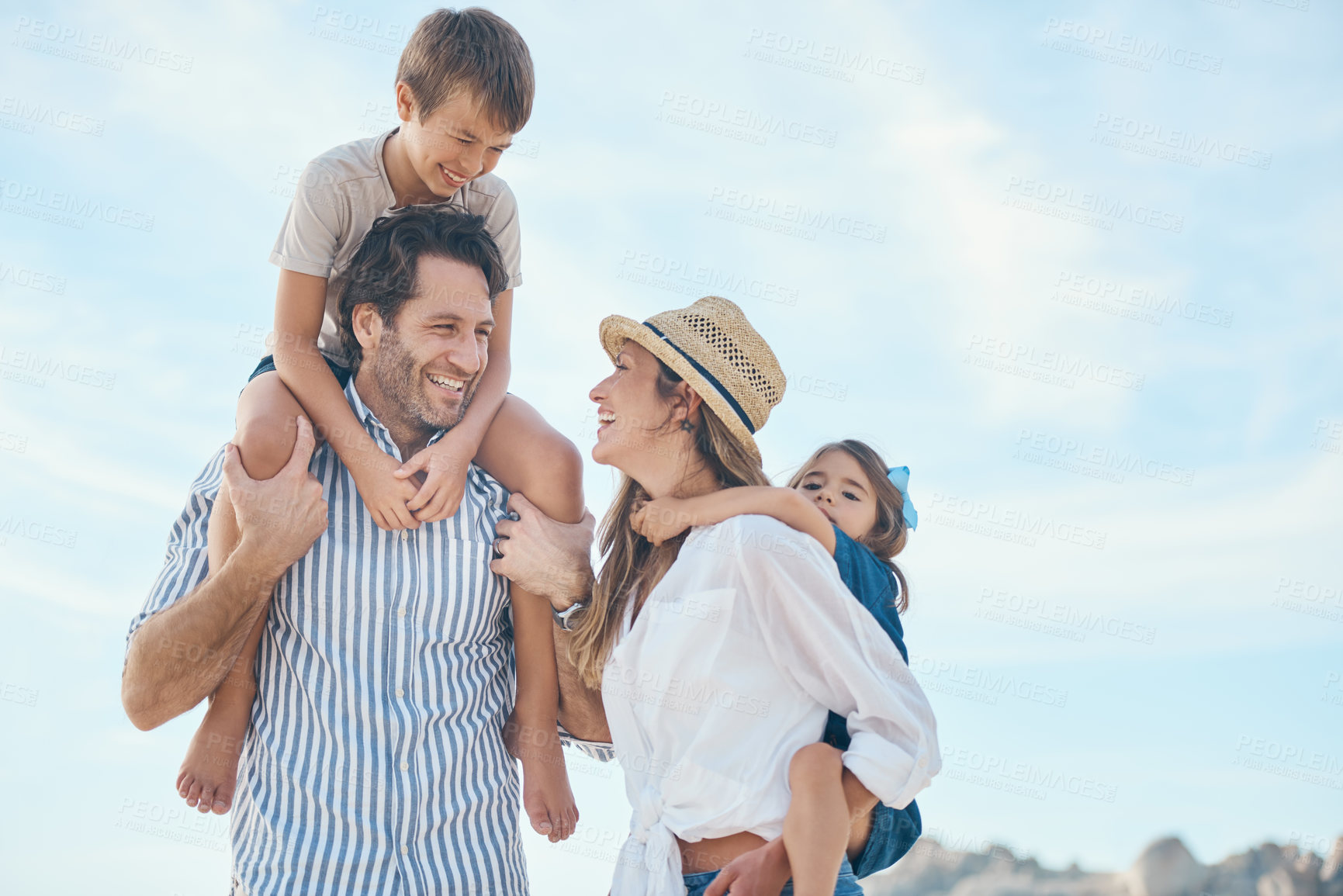 Buy stock photo Family, happy and carrying on beach for travel, holiday and bonding together in summer with sunshine. Mom, dad and kids by ocean for relax, vacation and relationship with shoulder ride and blue sky