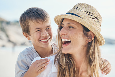 Buy stock photo Cropped shot of an attractive young mother bonding with her son and giving him a piggyback ride on the beach