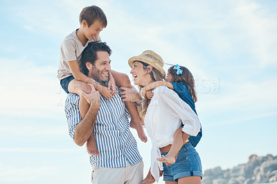 Buy stock photo Cropped shot of a happy young couple carrying their two children during an enjoyable day on the beach