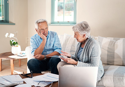 Buy stock photo Shot of a senior couple having a disagreement while going through paperwork at home