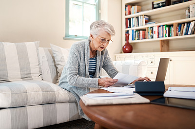Buy stock photo Shot of a senior woman going through paperwork at home
