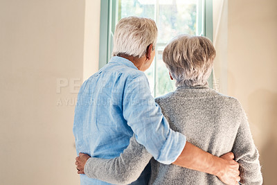 Buy stock photo Rearview shot of an affectionate senior couple looking out of a window together at home