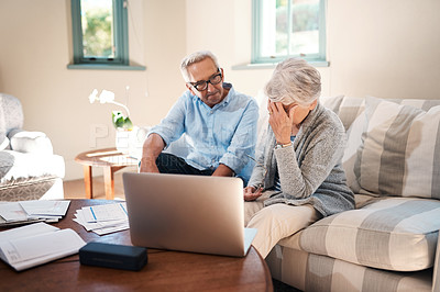 Buy stock photo Shot of a senior couple having a disagreement while going through paperwork at home