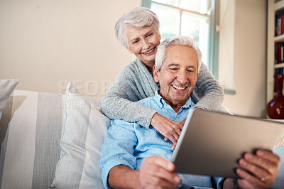 Buy stock photo Shot of a senior couple using a digital tablet together in their living room at home