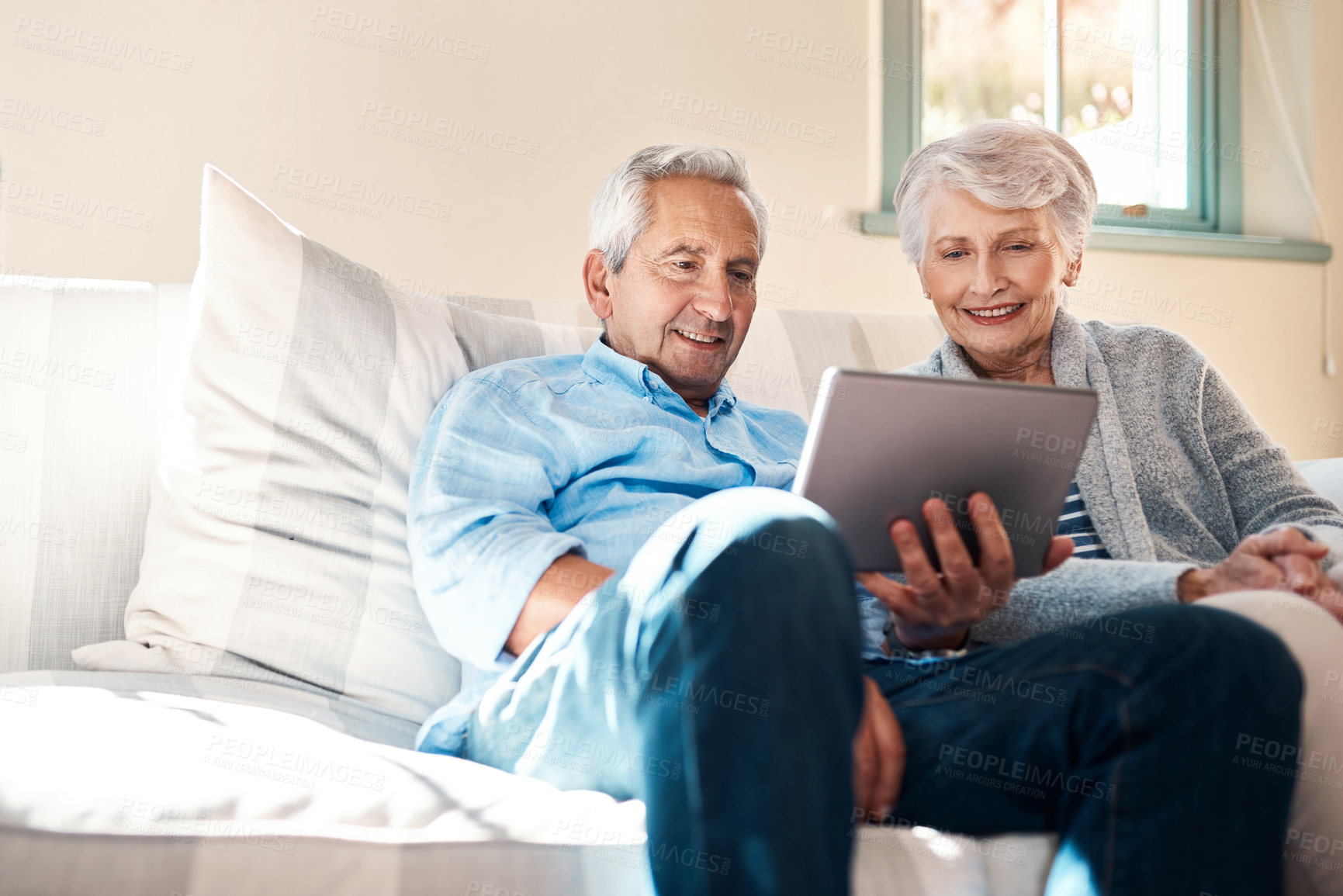 Buy stock photo Shot of a senior couple using a digital tablet together in their living room at home