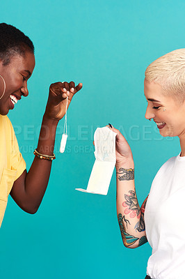 Buy stock photo Studio shot of two young women comparing sanitary wear against a turquoise background