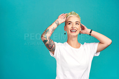 Buy stock photo Studio shot of a young woman putting a crown her head against a turquoise background