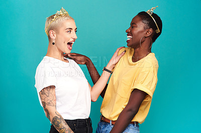 Buy stock photo Studio shot of two young women wearing crowns against a turquoise background