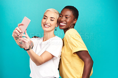 Buy stock photo Studio shot of two young women taking selfies together against a turquoise background