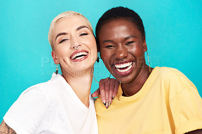 Buy stock photo Studio shot of two happy young women posing together against a turquoise background