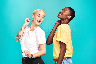 Buy stock photo Studio shot of two young women dancing together against a turquoise background
