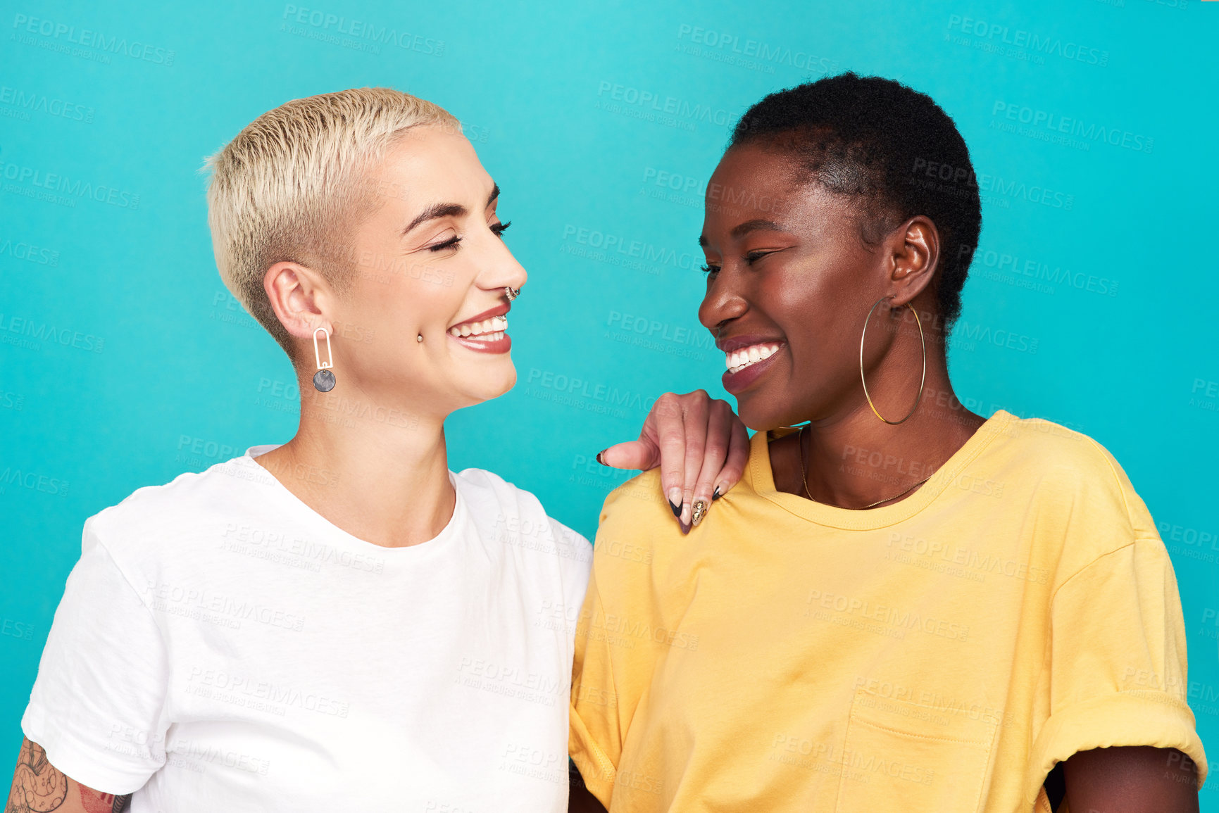 Buy stock photo Studio shot of two happy young women posing together against a turquoise background