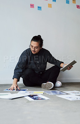 Buy stock photo Full length shot of a creative young businessman sitting on the floor and planning and brainstorming ideas at work