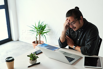 Buy stock photo Shot of a handsome young businessman looking stressed out and suffering from a headache at work