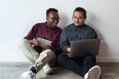 Buy stock photo Full length shot of two young businessmen sitting in the floor and using their digital devices together at work