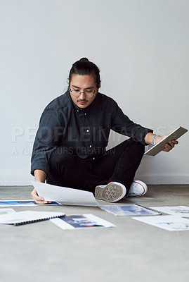 Buy stock photo Full length shot of a handsome creative young businessman sitting on the floor and planning and brainstorming ideas at work