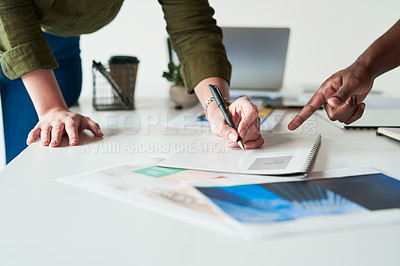 Buy stock photo Shot of two unrecognizable business people planning and going over paperwork and ideas together a work