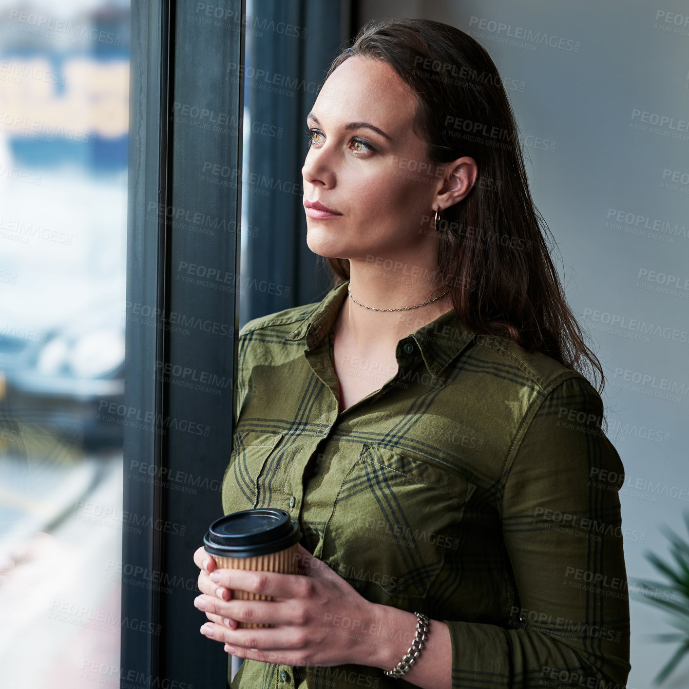 Buy stock photo Shot of an attractive young businesswoman drinking coffee and looking out the window of her office