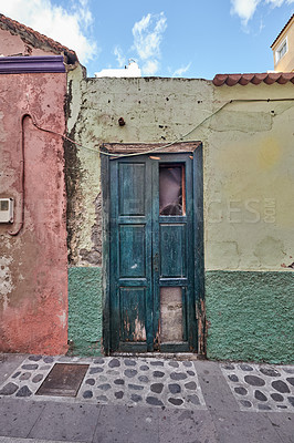 Buy stock photo A damaged door on an old abandoned house in a small village. Broken wooden door of an old weathered building with scratched paint in a historic town. Flaking and decaying entrance of a home