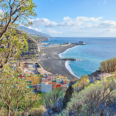 Buy stock photo An ocean coast with black beach sand on Puerto de Tazacorte beach from above. Colorful town houses or holiday resort accommodation near the seaside in a beautiful tourism destination, La Palma, Spain