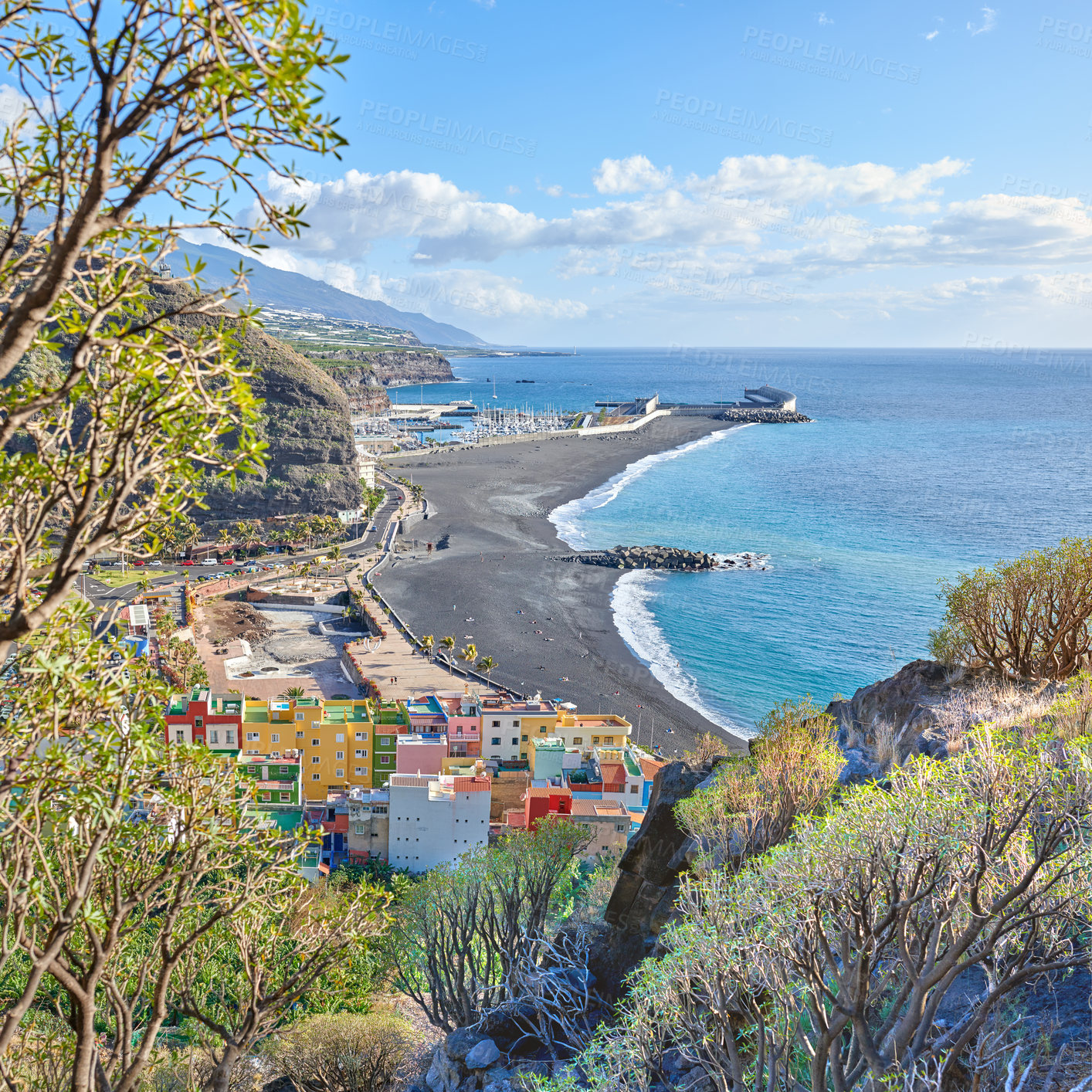 Buy stock photo An ocean coast with black beach sand on Puerto de Tazacorte beach from above. Colorful town houses or holiday resort accommodation near the seaside in a beautiful tourism destination, La Palma, Spain