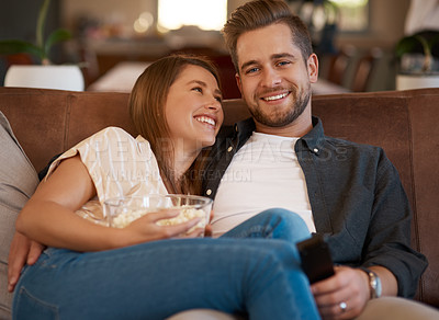 Buy stock photo Cropped shot of a young couple relaxing with popcorn on the sofa at home