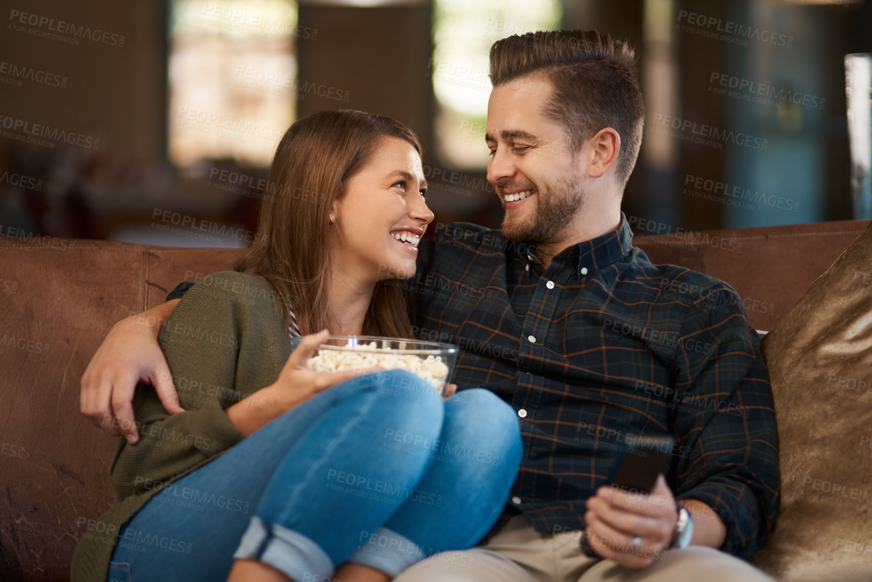 Buy stock photo Couple, hug and popcorn or remote for tv on couch, relax and bonding with movie snack in home. Happy people, embrace and love for series or laugh for comedy, streaming and food for comic or marriage