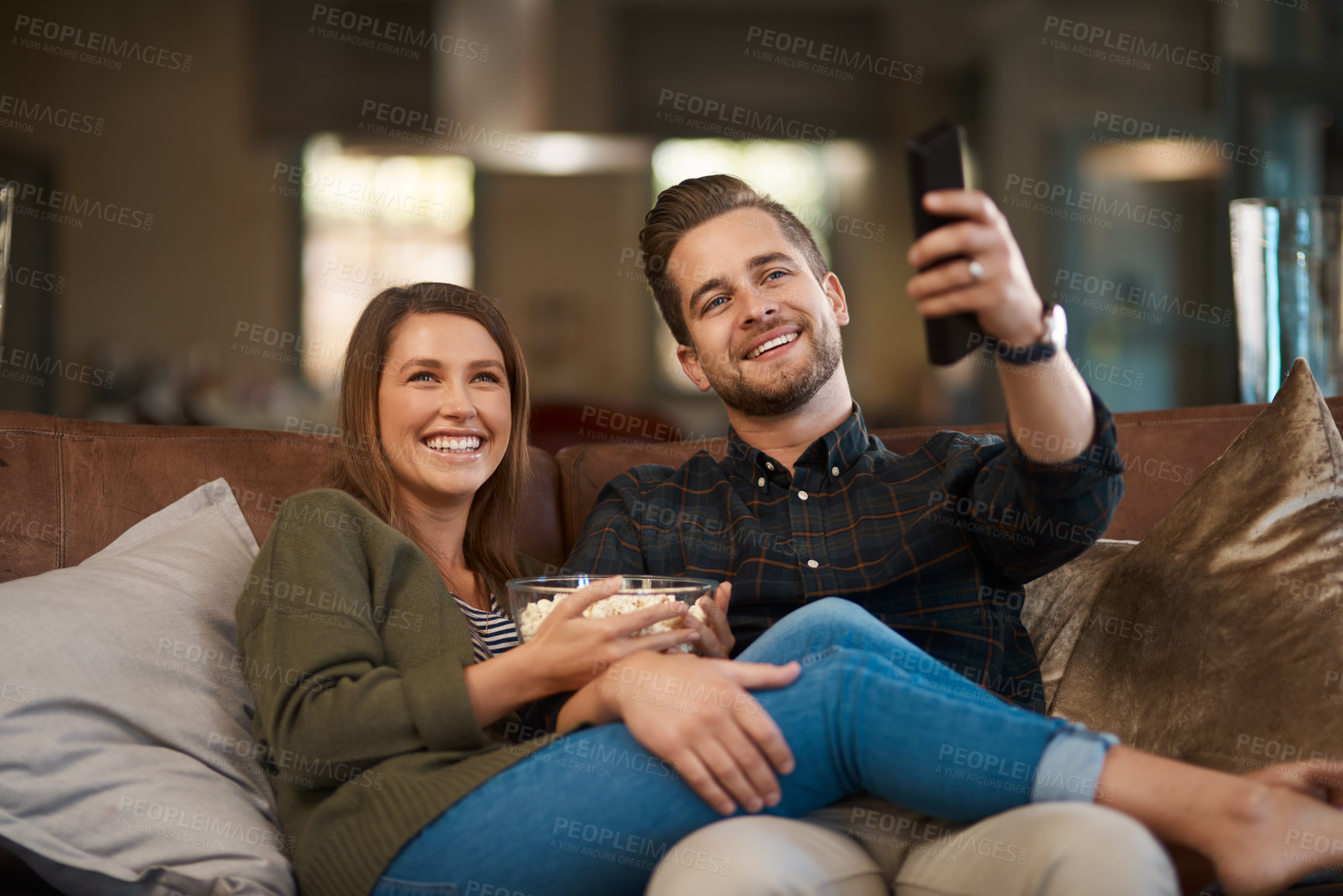 Buy stock photo Couple, popcorn and remote control for watching tv on the couch, relax at home for bonding and streaming. Movie, show or video, people and time together with corn snack, change channel and smile