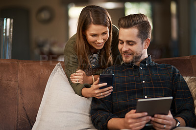 Buy stock photo Cropped shot of a young couple using a cellphone and a digital tablet at home