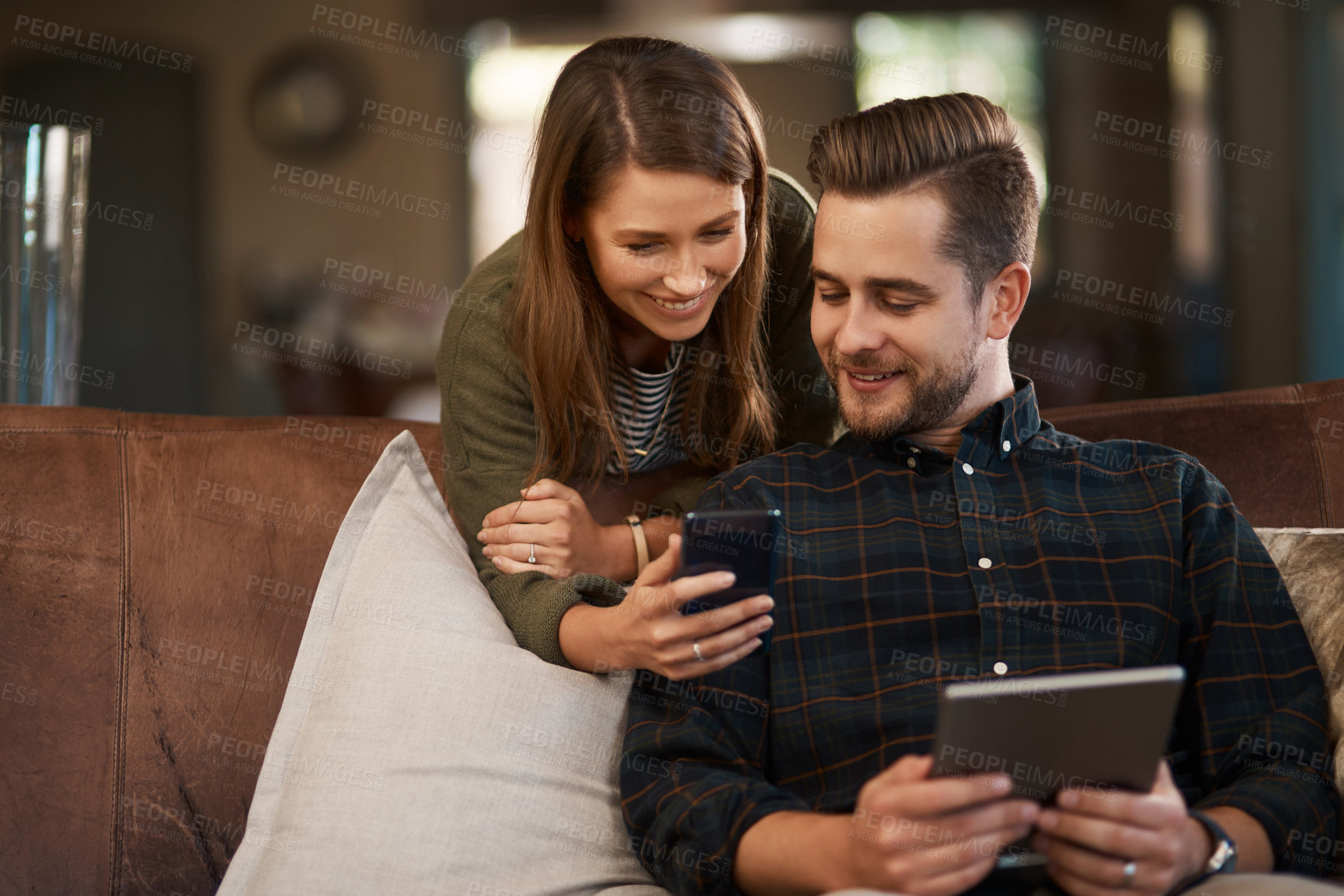Buy stock photo Cropped shot of a young couple using a cellphone and a digital tablet at home