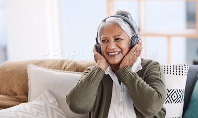 Buy stock photo Shot of a senior woman wearing headphones while listening to music at home