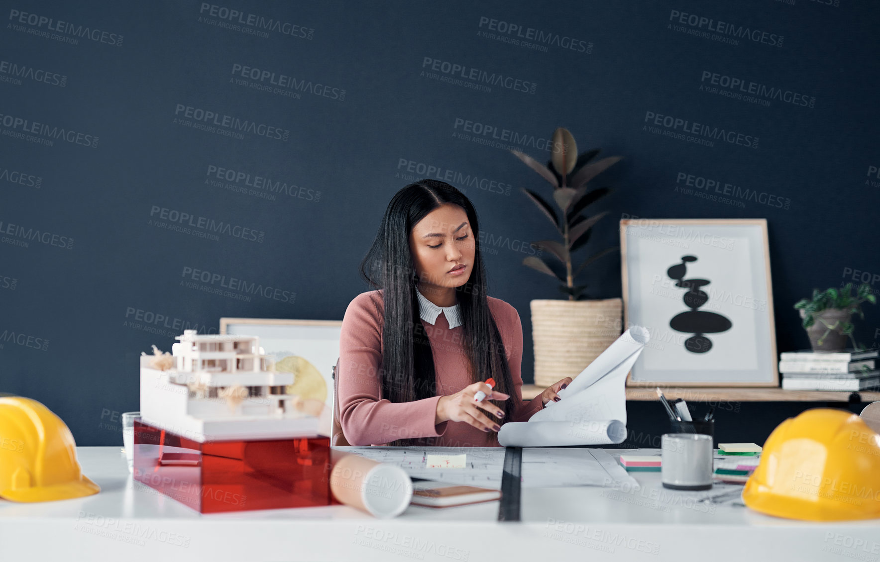 Buy stock photo Shot of an attractive young female architect going over paperwork and designs in her office