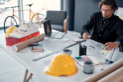 Buy stock photo Shot of a handsome young architect working on building plans and designs in his office
