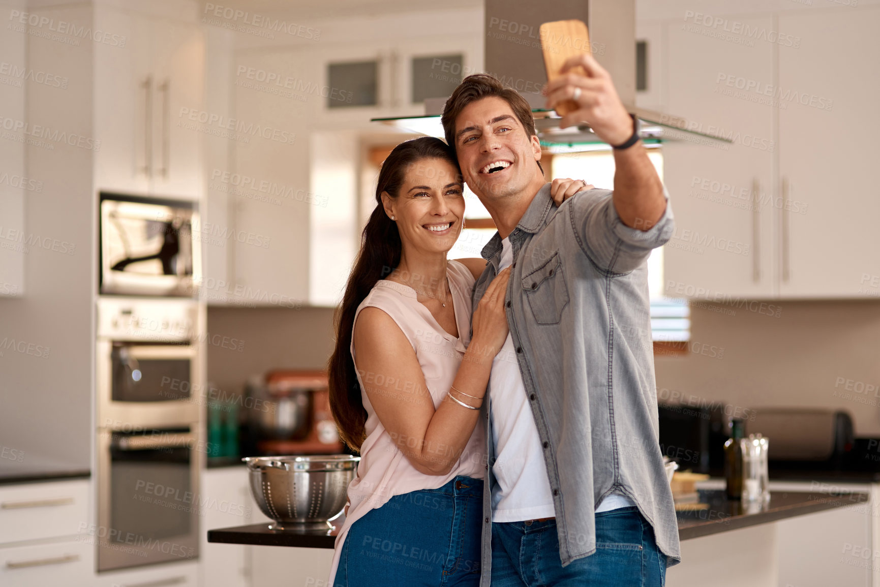 Buy stock photo Couple, home kitchen and selfie with mobile for profile picture together, social media post and digital gallery. Apartment, woman smile and man for photo on phone with happy memory, relax and love