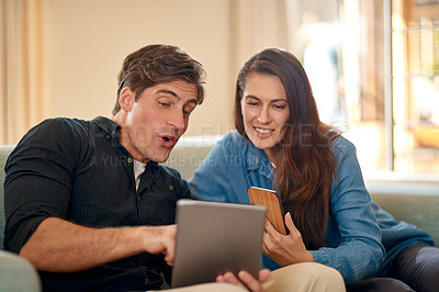 Buy stock photo Cropped shot of a couple using wireless technology while relaxing on the sofa at home