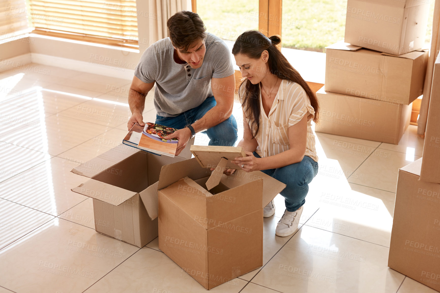 Buy stock photo Shot of a couple unpacking boxes in their new home