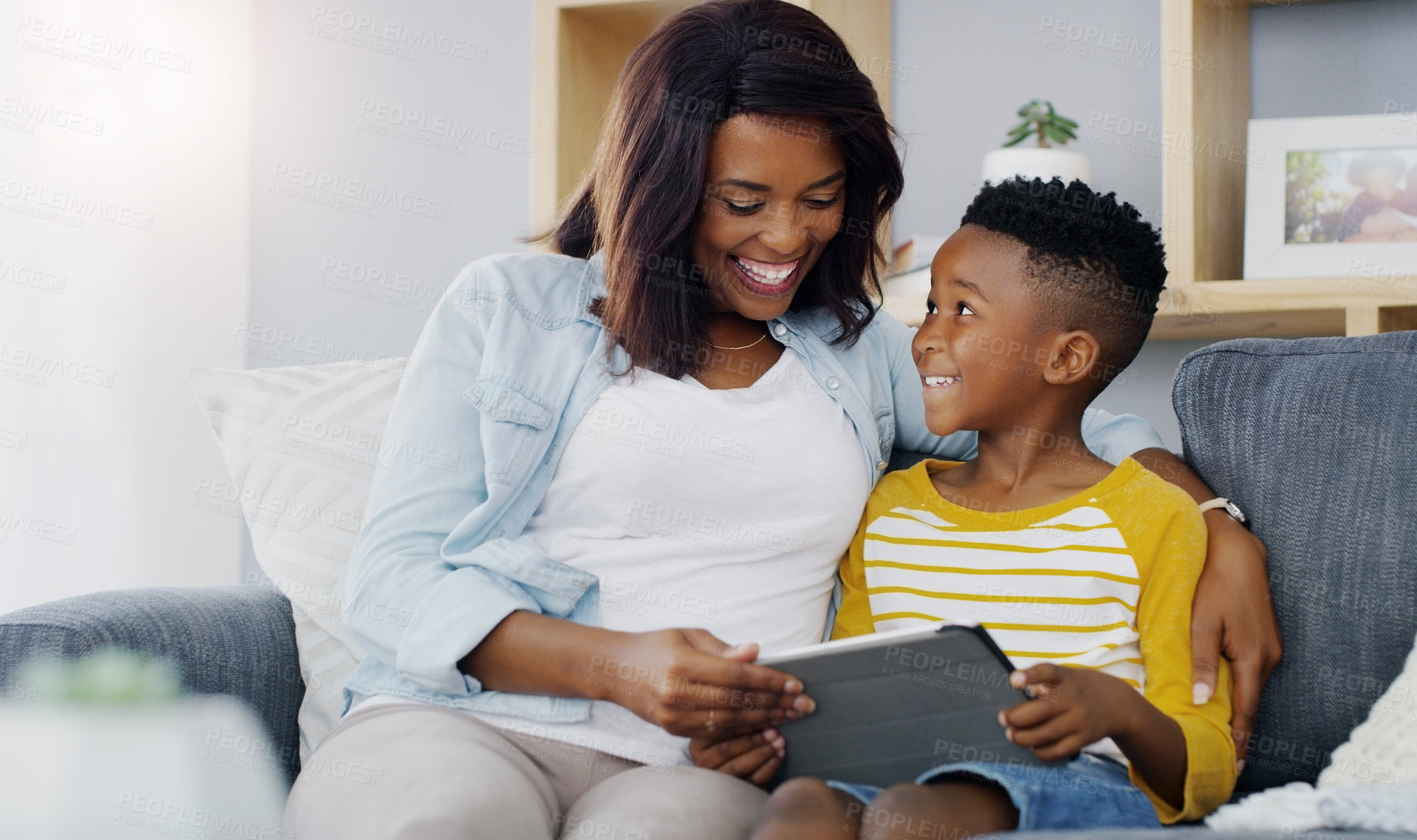 Buy stock photo Shot of an adorable little boy using a digital tablet with his mother at home