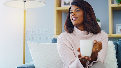 Buy stock photo Shot of an attractive young woman enjoying a warm cup of coffee while relaxing at home