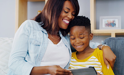 Buy stock photo Shot of an adorable little boy using a digital tablet with his mother while spending quality time together at home