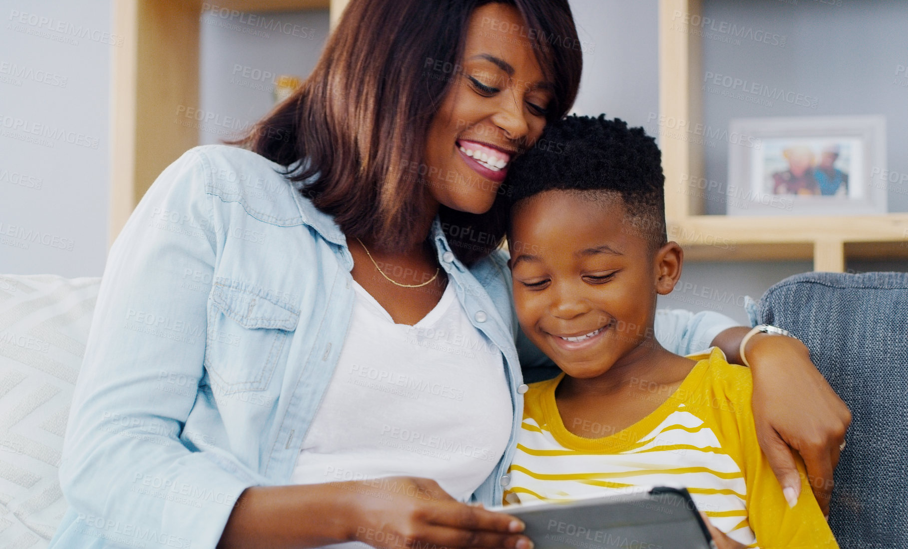 Buy stock photo Shot of an adorable little boy using a digital tablet with his mother while spending quality time together at home