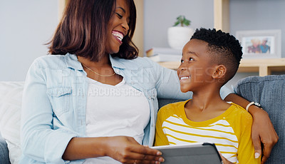 Buy stock photo Shot of an adorable little boy using a digital tablet with his mother at home