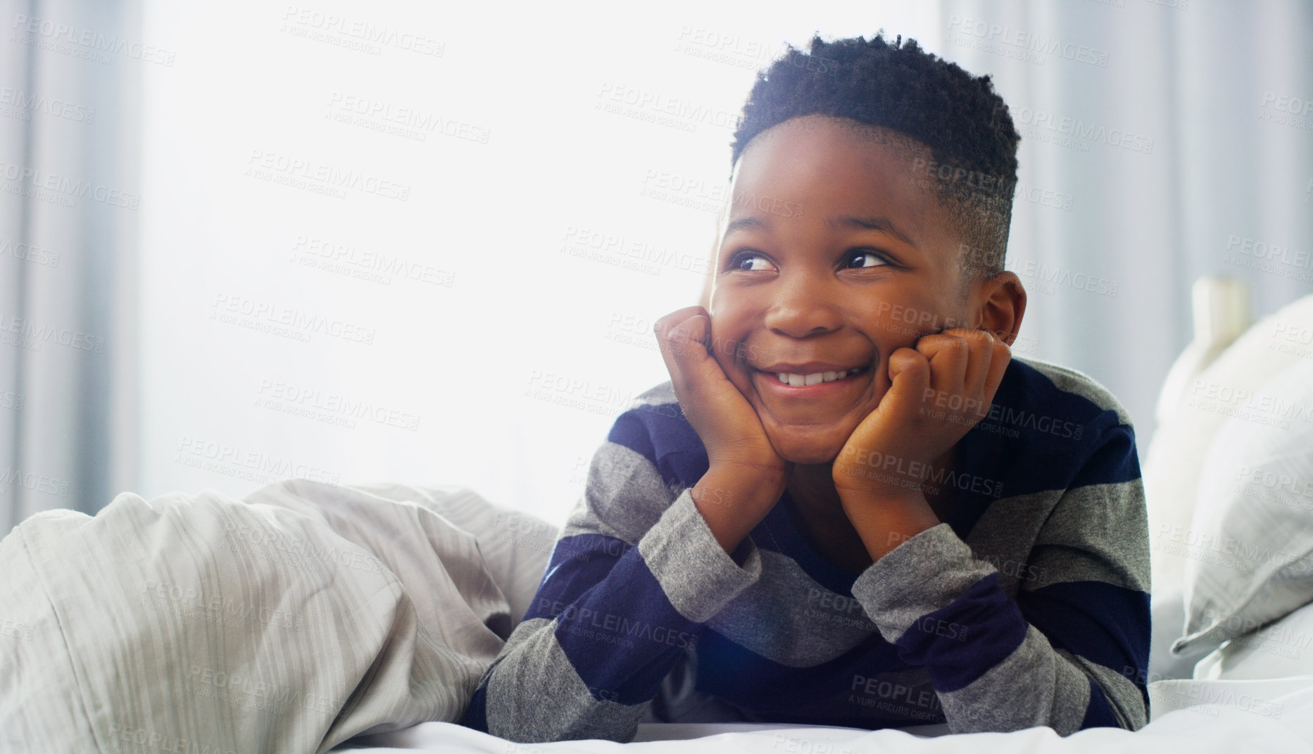 Buy stock photo Shot of an adorable little boy lying down on his bed at home in the morning