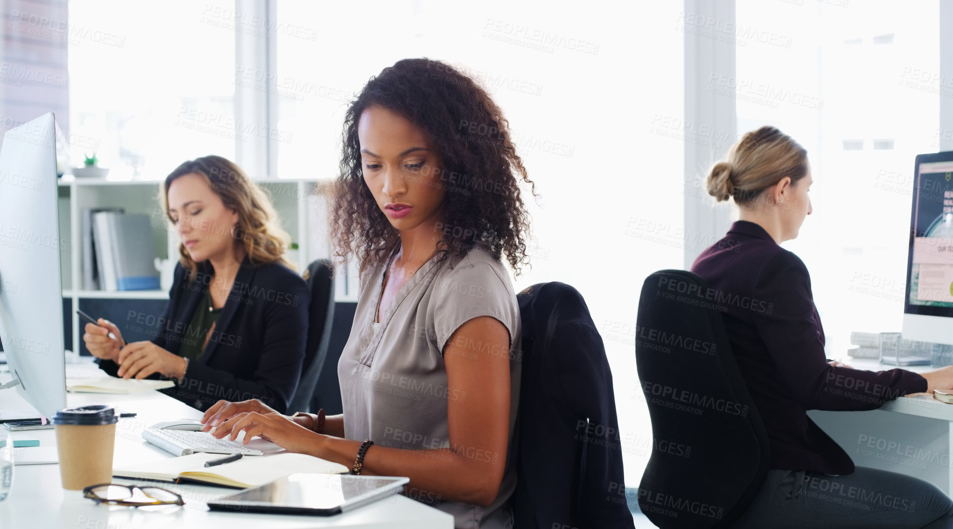 Buy stock photo Shot of a group of young businesswomen using their computers in a modern office