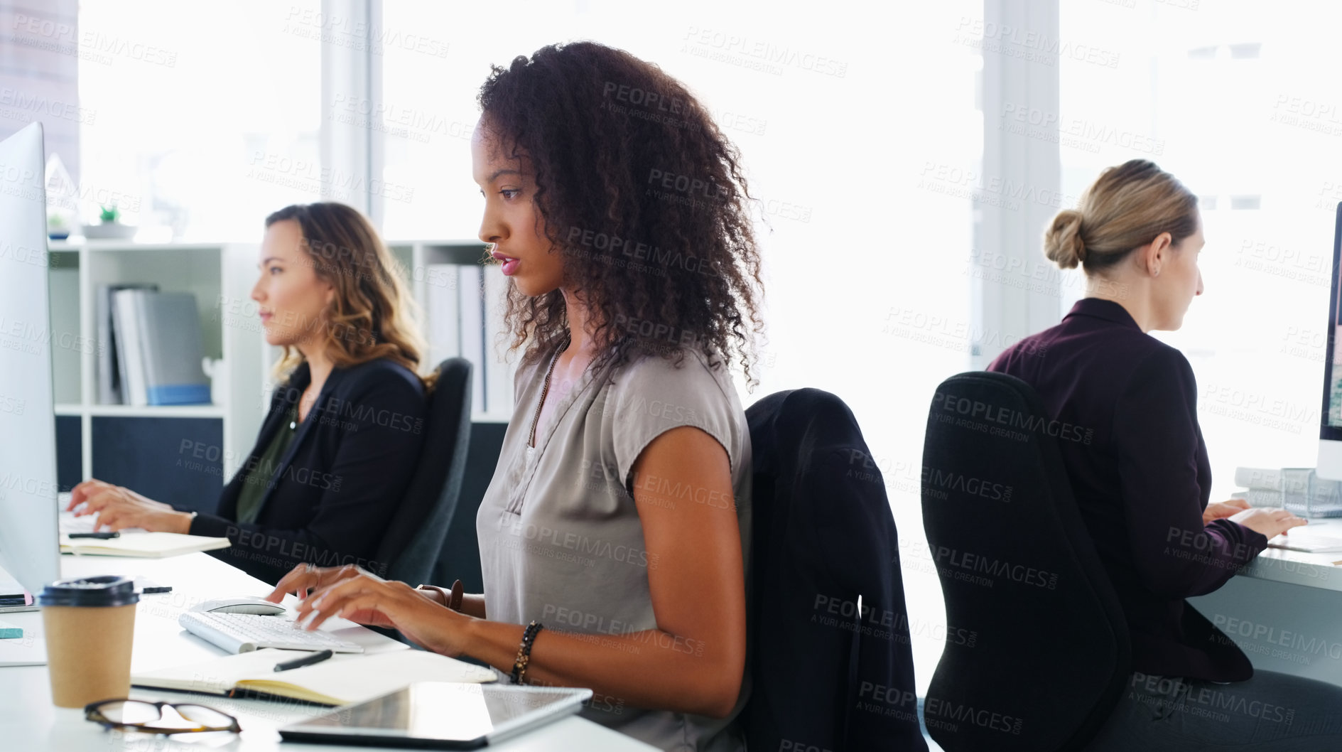 Buy stock photo Shot of a group of young businesswomen using their computers in a modern office