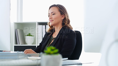Buy stock photo Shot of a confident young businesswoman using a computer at her desk in a modern office