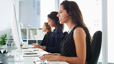 Buy stock photo Shot of a young woman using a computer and headset in a modern office