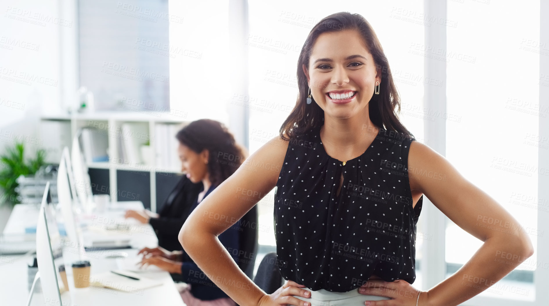 Buy stock photo Portrait of a confident young businesswoman working in a modern office with her colleague in the background