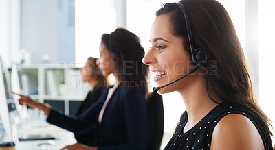 Buy stock photo Shot of a young woman using a computer and headset in a modern office