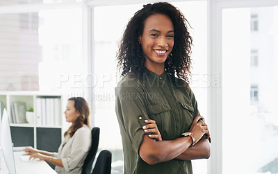 Buy stock photo Portrait of a confident young businesswoman working in a modern office with her colleague in the background