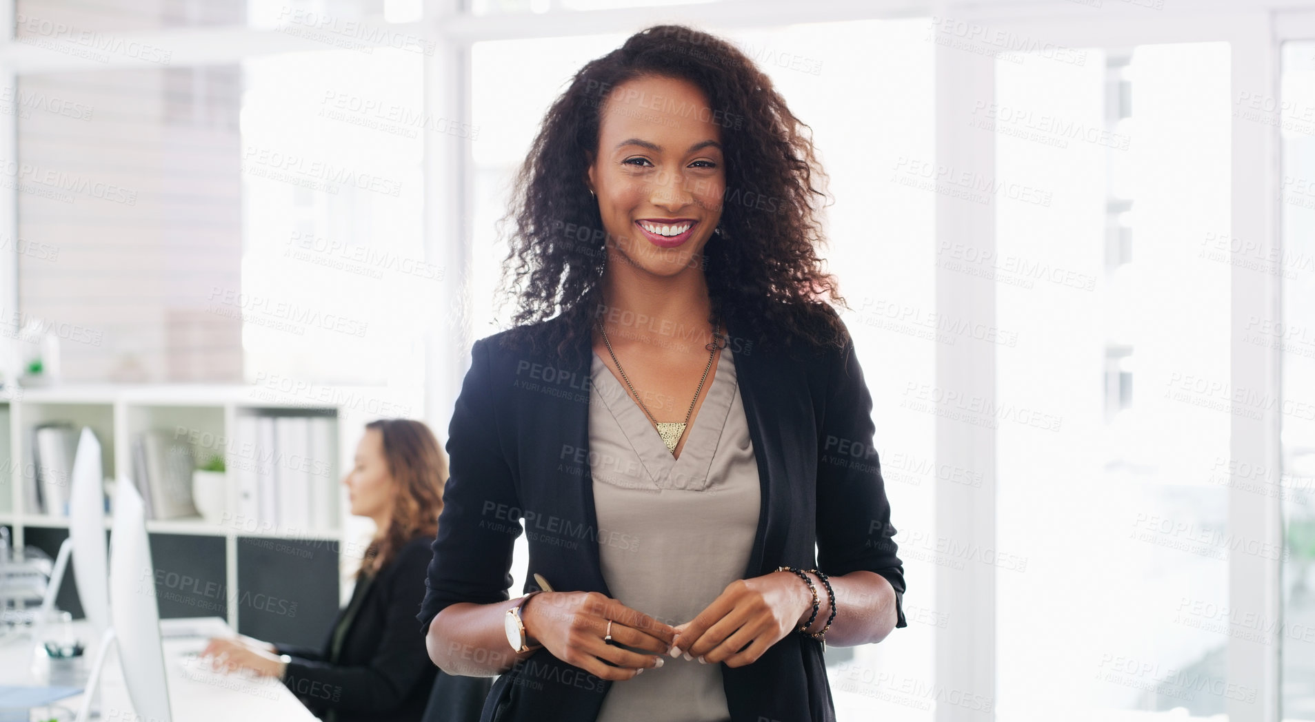 Buy stock photo Portrait of a confident young businesswoman working in a modern office with her colleague in the background